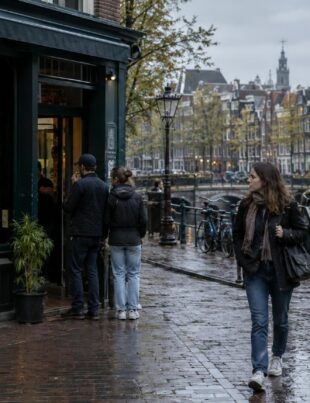 Amsterdam street with coffeeshop storefront and pedestrians in overcast light