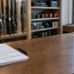 ATF updates firearm transaction form after medical cannabis rescheduling—changes? Gun store counter with firearm transaction forms and firearms in background