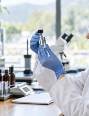 Scientist examining hemp extract vial in a bright laboratory setting