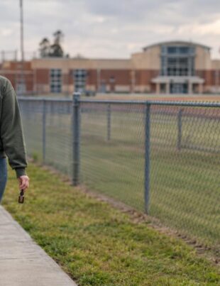 Adult walking near Louisiana high school with CBD oil bottle in hand