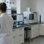 Cannabis testing laboratory with technician handling flower samples under natural light