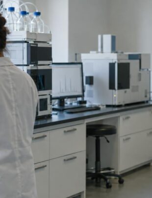 Cannabis testing laboratory with technician handling flower samples under natural light
